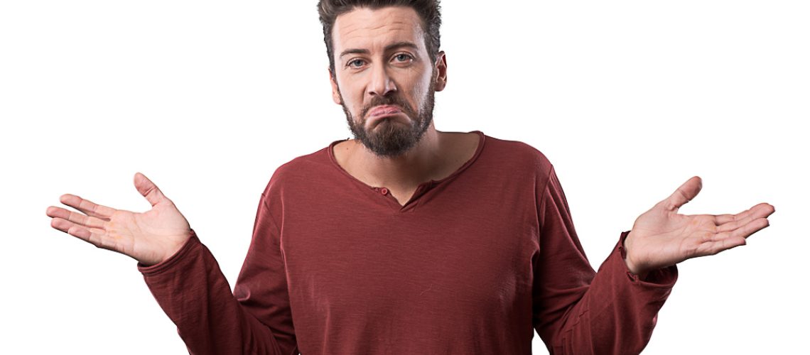 Young confused man shrugging and looking at camera